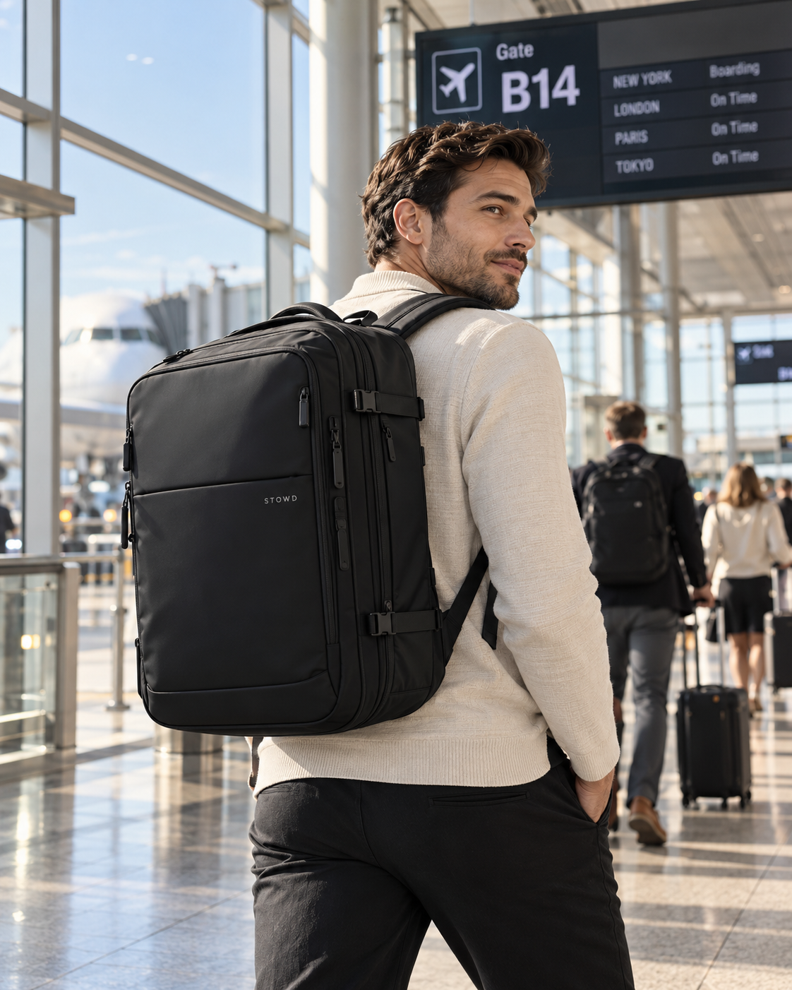 Traveller wearing a black STOWD ONE backpack inside an airport terminal